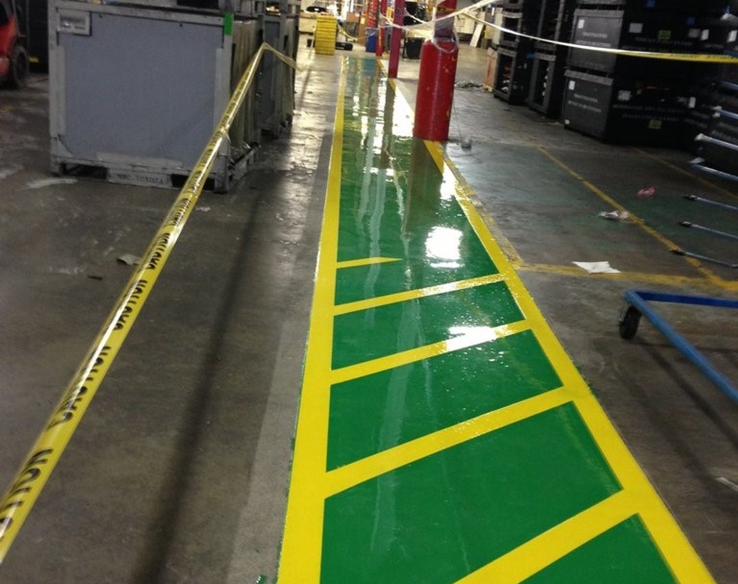 Gray epoxy floor with yellow safety walkway markings in a Toronto warehouse